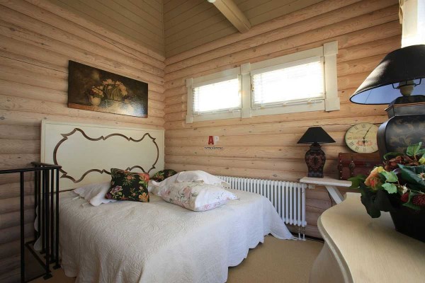 La décoration des chambres à coucher dans les maisons en rondins n'est pas différente: des tons clairs et calmes et plusieurs accents de couleur