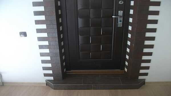 La pente extérieure de la porte d'entrée peut être finie avec de la pierre ou des carreaux