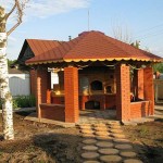 Colonnes puissantes avec balustrade en demi-brique entre elles. Si nécessaire, ce gazebo d'été peut être facilement converti en gazebo d'hiver: installez des fenêtres à double vitrage ou des cadres en bois