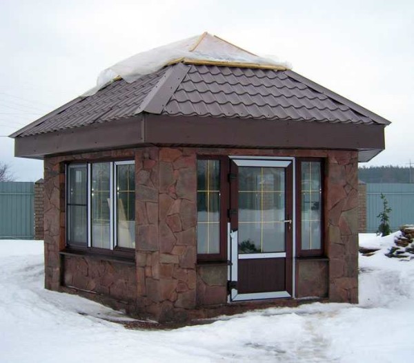 Un exemple de gazebo vitré majuscule garni de pierres sauvages. N'importe quel bloc de construction peut être en bas. Vitrage avec fenêtres à double vitrage