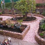 Des briques en céramique de différentes couleurs et des chemins parsemés de gravier teinté et une cour avec un parterre de fleurs a fière allure