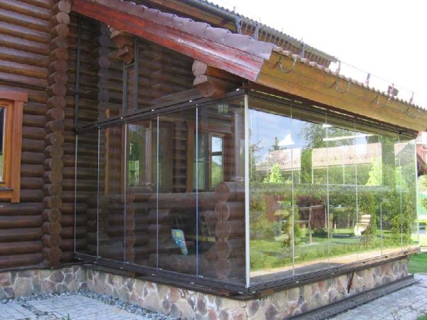 Le vitrage sans cadre de la véranda en combinaison avec une maison en rondins n'est pas la meilleure solution