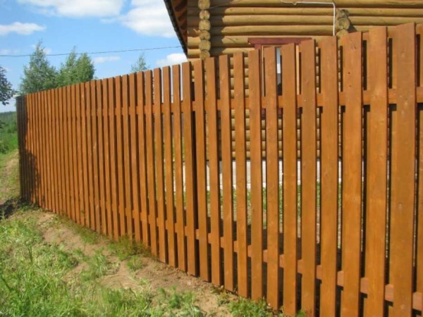 Une simple clôture à piquets faite de planches imprégnées d'un antiseptique tonifiant semble solide