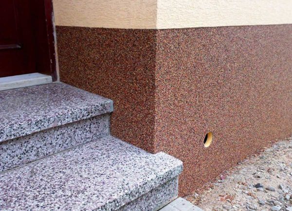 Un exemple de décoration d'une maison avec du plâtre décoratif de l'extérieur: plâtre de pierre au sous-sol, au-dessus - sur les murs - scolyte