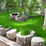 Une clôture intéressante autour de la pelouse - les pots de fleurs faits de souches alternent simplement avec des terrasses