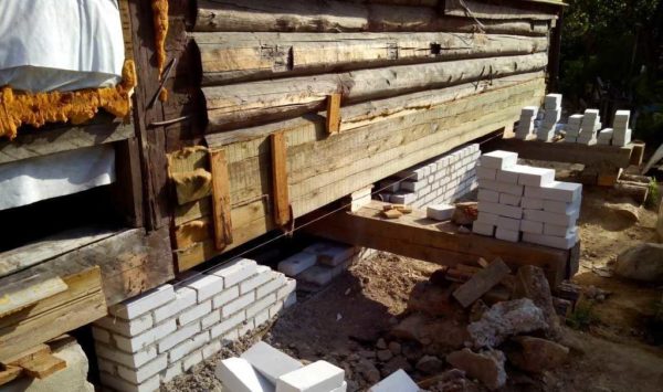 Les couronnes inférieures de la maison en rondins ont pourri, elles ont été enlevées avant d'être soulevées et remplacées par une barre