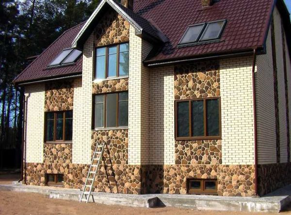 La brique se marie bien avec la pierre. Sur la photo - une maison en briques blanches avec des garnitures en pierre sauvage