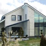 Maison en brique blanche dans un style moderne. La luminosité de la façade est donnée par une finition contrastée