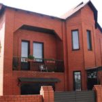La façade d'une maison en brique rouge de deux étages avec des caractéristiques caractéristiques d'un style moderne, mais un caractère individuel clair